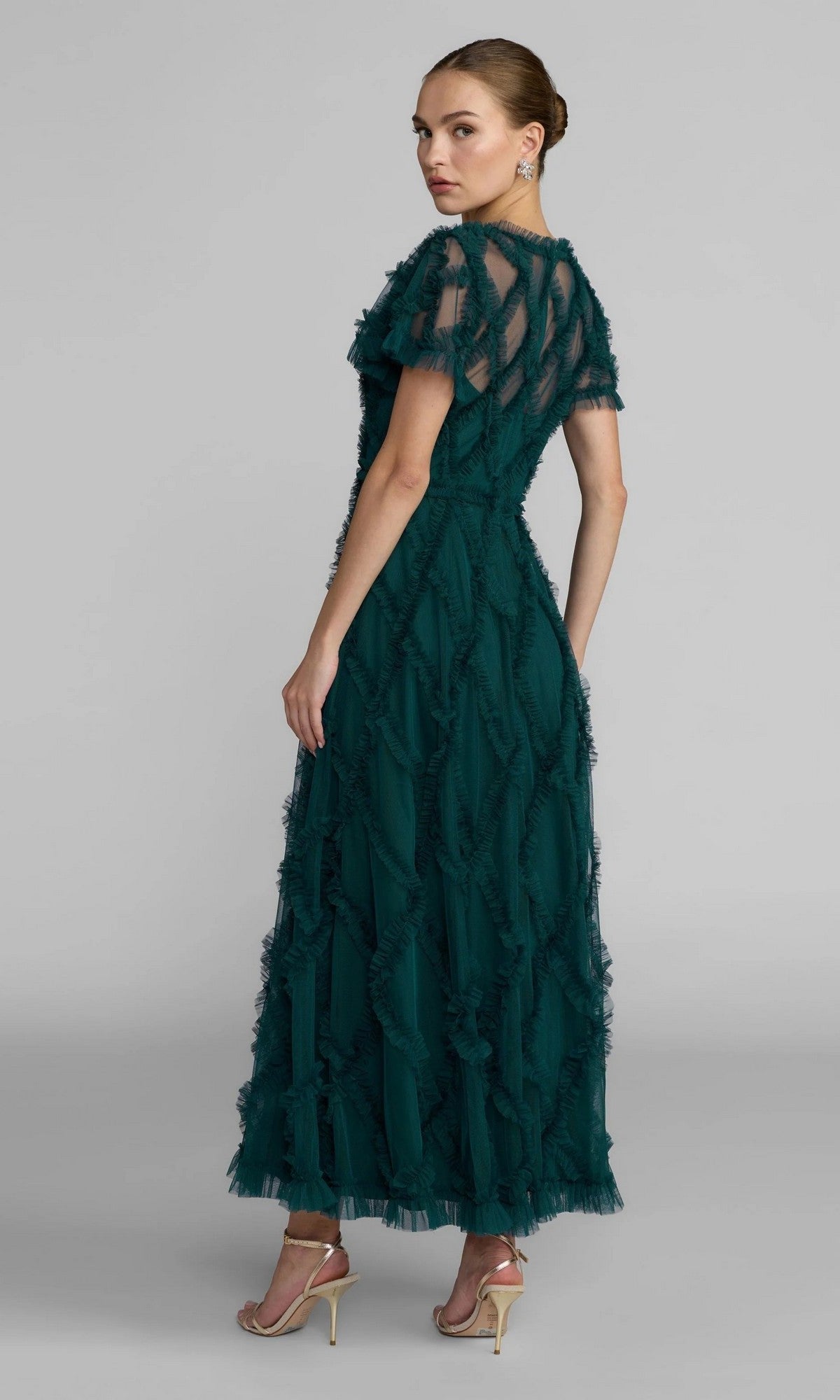 A woman in profile looks over her shoulder, modeling the Mac Duggal 8278 Short Sleeve Midi Formal Dress in teal, featuring ruffles and a sheer overlay.